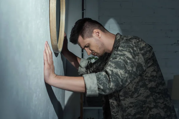 Vista lateral del soldado con trastorno de estrés postraumático que sufre de flashbacks en casa por la noche - foto de stock