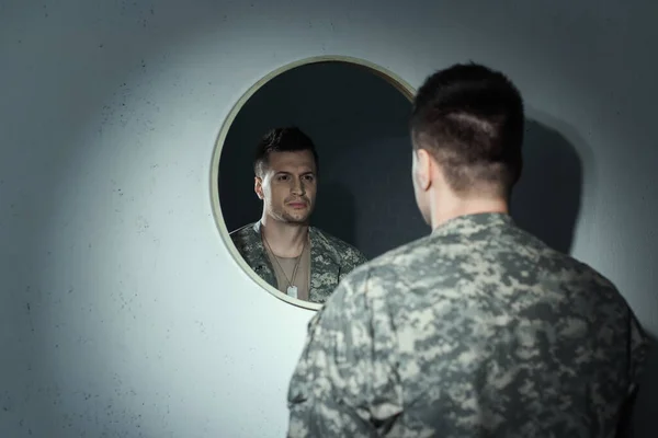 Размытый военный ветеран с эмоциональным расстройством смотрит в зеркало дома — стоковое фото