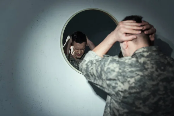 Stressed military veteran suffering from post traumatic stress disorder near mirror at home at night — Stock Photo