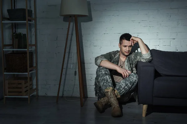 Депрессивный военный ветеран в форме сидит на полу дома — стоковое фото