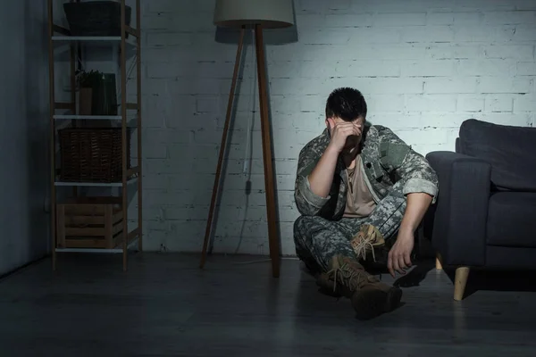 Soldado en uniforme militar que sufre de depresión en casa por la noche - foto de stock
