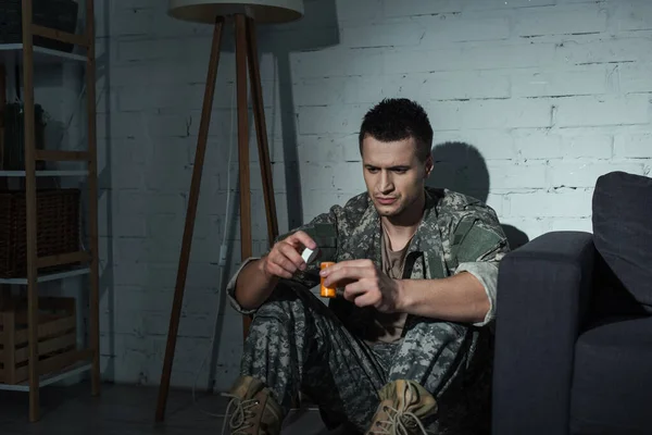 Soldat en uniforme tenant des médicaments alors qu'il souffrait de stress post-traumatique à la maison la nuit — Photo de stock