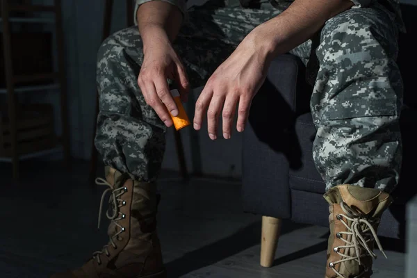 Cropped view of soldier in uniform with ptsd holding antidepressants at home — Stock Photo