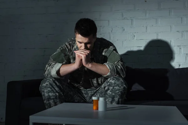 Militar con disociación mental sentado cerca de pastillas en casa por la noche - foto de stock