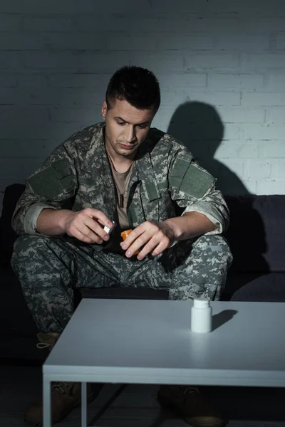 Military veteran with mental problem holding pills from ptsd at home at night — Stock Photo