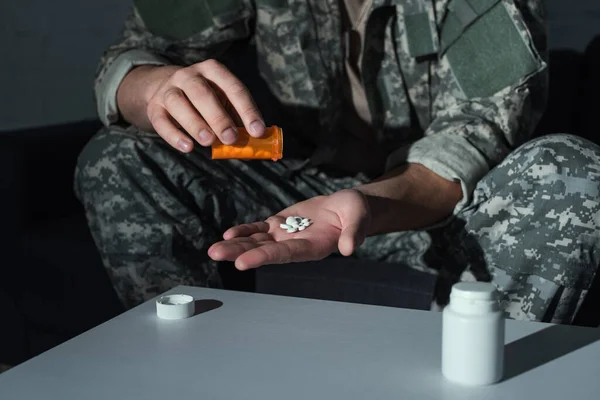 Vista recortada de soldado con trastorno de estrés postraumático sosteniendo pastillas en casa — Stock Photo