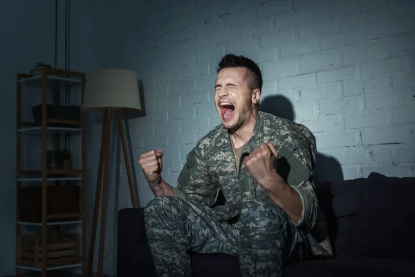 Veterano militar con trastorno mental gritando en casa por la noche - foto de stock