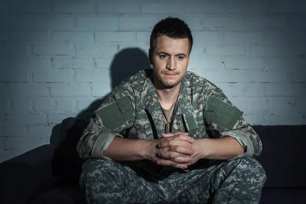 Frustrierter Soldat mit psychischer Störung sitzt nachts zu Hause auf Couch — Stockfoto