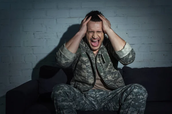 Military veteran with post traumatic stress disorder screaming and touching head at home at night — Stock Photo
