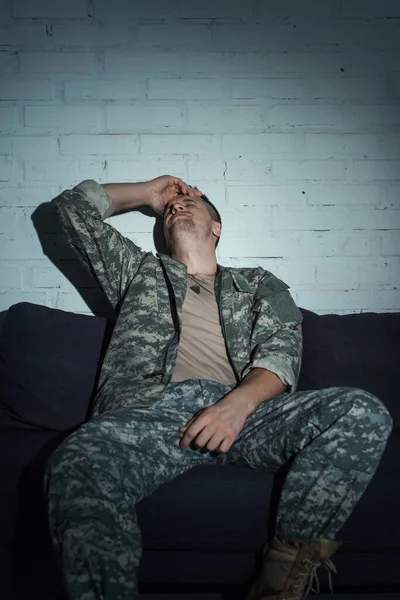 Depressiver Militärveteran mit psychischer Störung sitzt nachts zu Hause auf Couch — Stockfoto