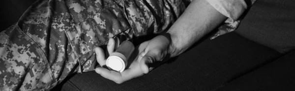 Foto monocromatica dell'uomo militare in camuffamento che tiene antidepressivi a casa, banner — Foto stock