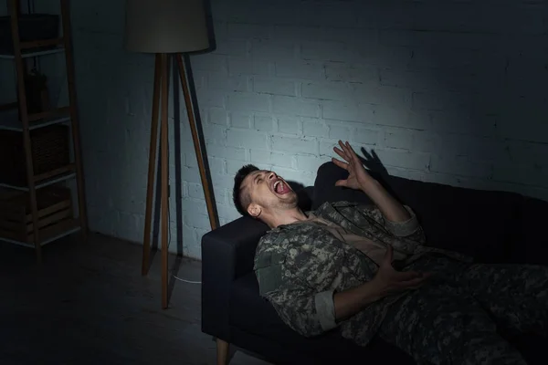 Irritated military man with post traumatic stress disorder screaming at home at night — Stock Photo
