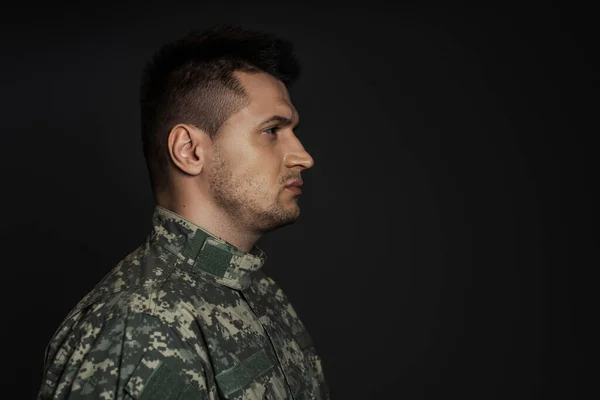 Perfil del hombre de servicio triste en uniforme militar aislado en negro - foto de stock