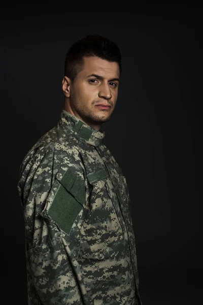Depressed soldier in uniform suffering from ptsd isolated on black — Stock Photo