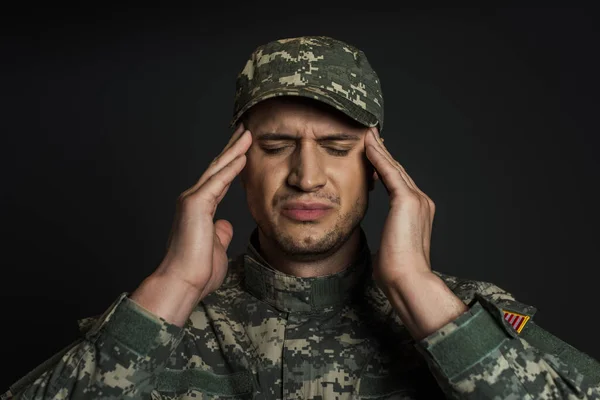 Soldado patriótico en uniforme de camuflaje y gorra que sufre de ptsd aislado en negro - foto de stock