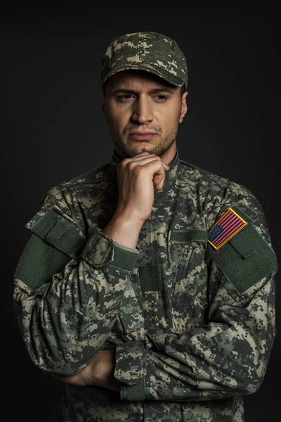 American soldier in camouflage uniform and cap suffering from ptsd isolated on black — Stock Photo
