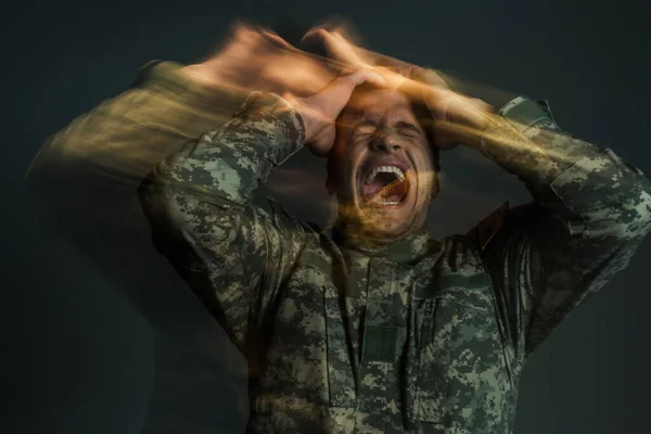 Longa exposição do soldado em gritos uniformes enquanto sofre de distúrbio de dissociação isolado em cinza escuro — Fotografia de Stock