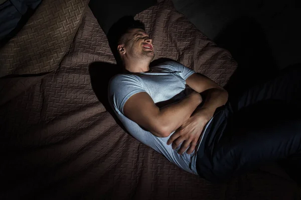 Vista superior do homem deprimido com os olhos fechados que sofrem de ataques de pânico enquanto deitado na cama à noite — Fotografia de Stock