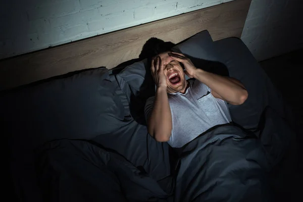 Top view of young man screaming while having nightmares and panic attacks at night — Stock Photo