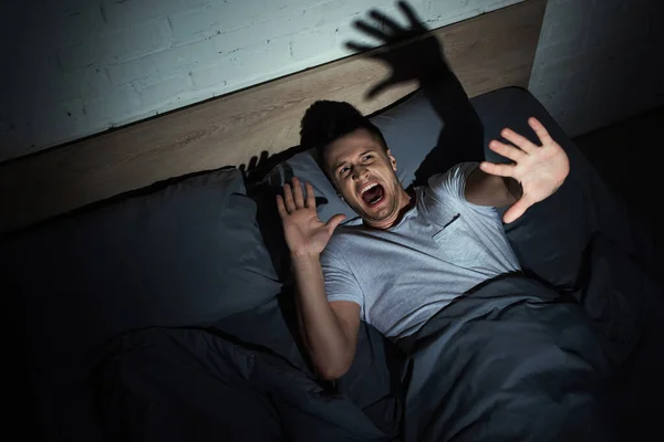 Top view of man having anxiety and screaming while having nightmares at night — Stock Photo
