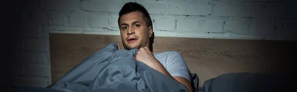 Стресс человек с паническими атаками, имеющие бессонницу во время лежания под одеялом, баннер — стоковое фото