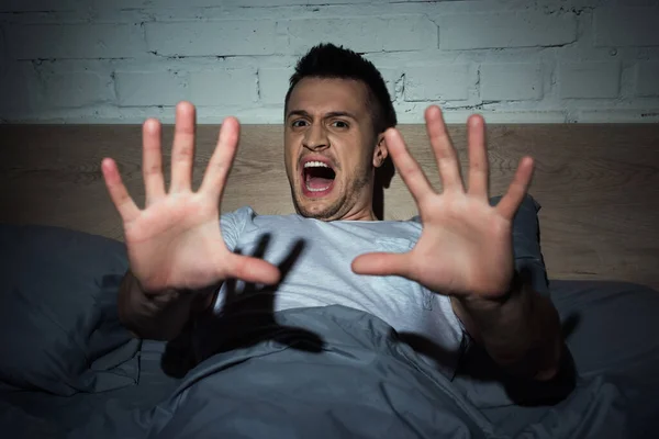Verängstigter junger Mann schreit, während er Albträume in der Nacht hat — Stockfoto