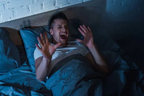 Top view of scared young man with ptsd having nightmares and screaming at night — Stock Photo