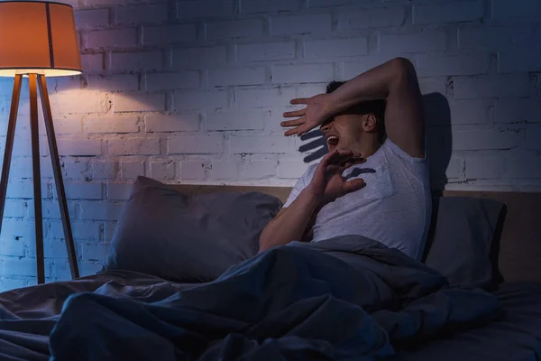 Verängstigter junger Mann mit ptsd mit Rückblenden, während er nachts schreit — Stockfoto