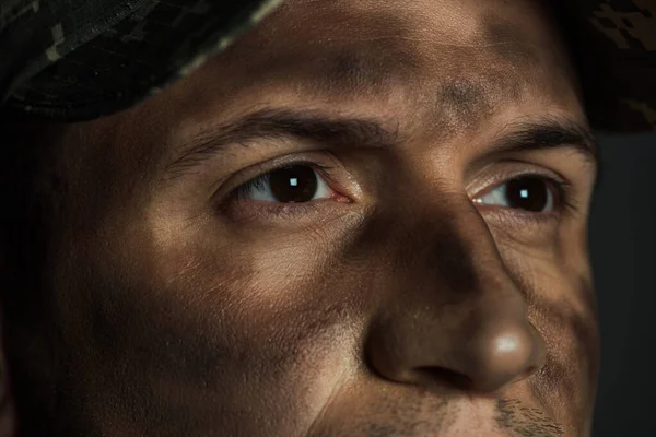 Vista da vicino degli occhi dell'uomo militare con sporcizia sul viso affetto da ptsd isolato su grigio — Foto stock