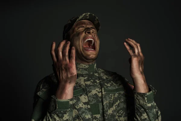 Military man with dirt on face screaming while suffering from ptsd isolated on grey — Stock Photo