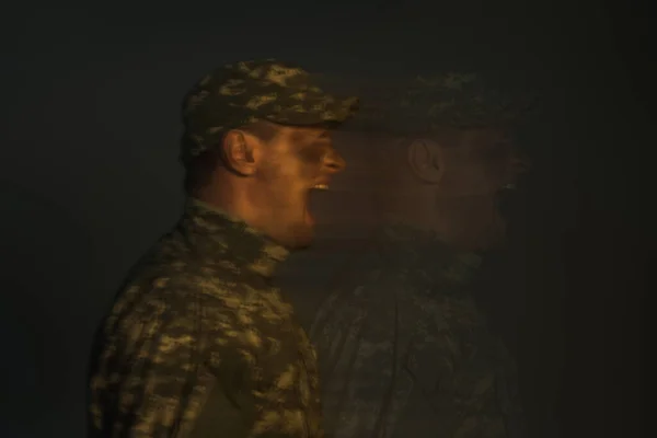 Longa exposição do soldado que sofre de transtorno dissociativo de identidade e gritando isolado no preto — Fotografia de Stock