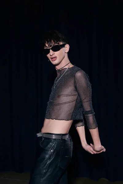 Fashionable and young homosexual man in sunglasses, sparking top and leather pants posing during lgbt pride month celebration isolated on black — Stock Photo