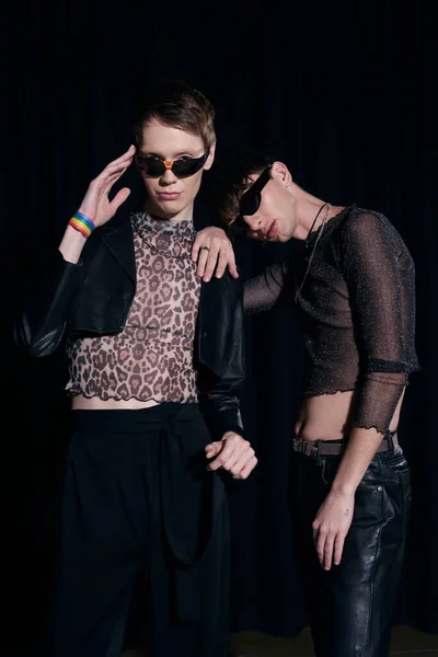 Trendy und junge schwule Freunde in Sonnenbrille und Party-Outfit posieren und in die Kamera schauen während der lgbt Stolz Monatsfeier isoliert auf schwarz — Stockfoto