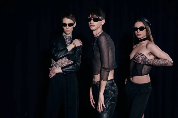 Gruppe von modischen homosexuellen Gemeinschaft in Sonnenbrille und Partykleidung posiert während der Feier lgbt Stolz Monat isoliert auf schwarz — Stockfoto