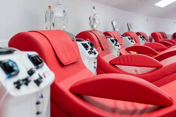 Reihe bequemer und ergonomischer medizinischer Stühle in der Nähe von automatisierten Transfusionsmaschinen und Tropfständern mit Infusionsbeutel im modernen Labor des Blutspendezentrums — Stockfoto