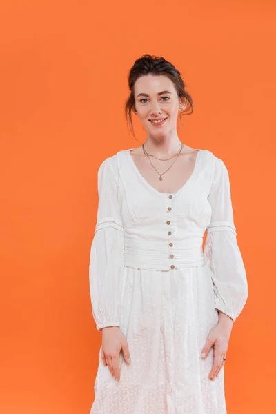 Літня мода, щаслива молода жінка в білій сонячній сукні посміхається і дивиться на камеру на помаранчевому фоні, яскравий фон, стильна позування, леді в білому — стокове фото