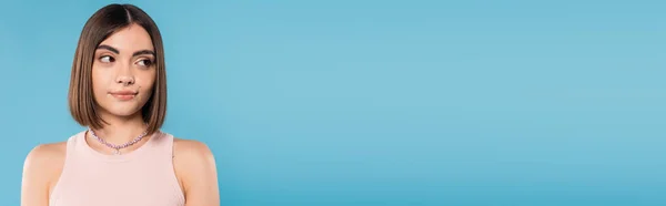 Zweifelnd, junge brünette Frau mit kurzen Haaren, die im Tank-Top steht und wegschaut auf blauem Hintergrund, Nasenpiercing, Jugend, Generation Z, Sommermode, skeptisch, Banner — Stockfoto