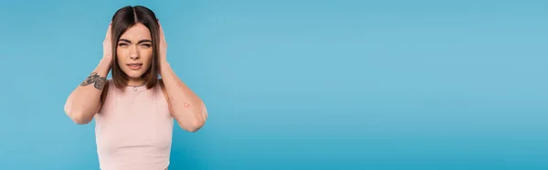 Migräne, tätowierte junge Frau mit Nasenpiercing und kurzen Haaren, die den Kopf berührt, während sie unter Kopfschmerzen auf blauem Hintergrund leidet, Generation z, Müdigkeit, Stress, Banner — Stockfoto