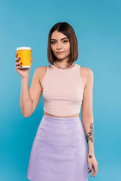 Coffee to go, attractive young woman with short hair, tattoos and nose piercing holding paper cup on blue background, generation z, summer trends, hipster style — Stock Photo