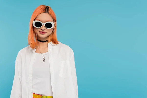 Happy face, cheerful asian young woman with dyed hair standing in casual attire and sunglasses, smiling on blue background, white shirt, choker necklace, red hair, generation z — Stock Photo