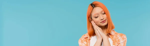 Sleepy asian woman, young model with dyed red hair holding hands near face and posing with closed eyes on vibrant blue background, generation z, casual attire, tired, fatigue, exhausted, banner — Stock Photo