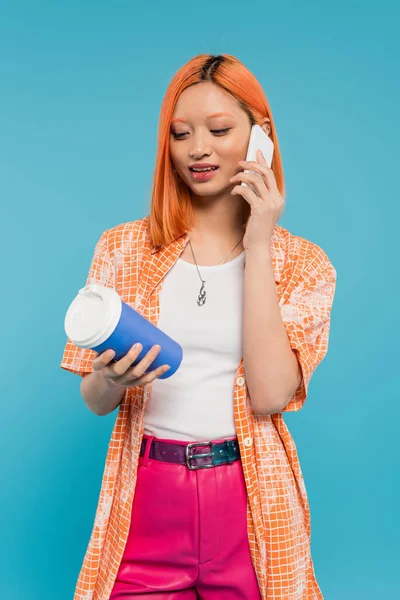Telefonema, mulher jovem asiática com cabelo vermelho segurando copo de papel e falando no smartphone no fundo azul, traje casual, geração z, cultura do café, bebida quente, copo de uso único — Fotografia de Stock