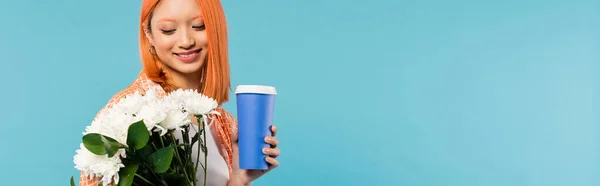 Весенние вибрации, счастливая азиатская и молодая женщина с рыжими волосами держа бумажную чашку и букет цветов на голубом фоне, случайный наряд, поколение z, культура кофе, кофе на вынос, баннер — стоковое фото