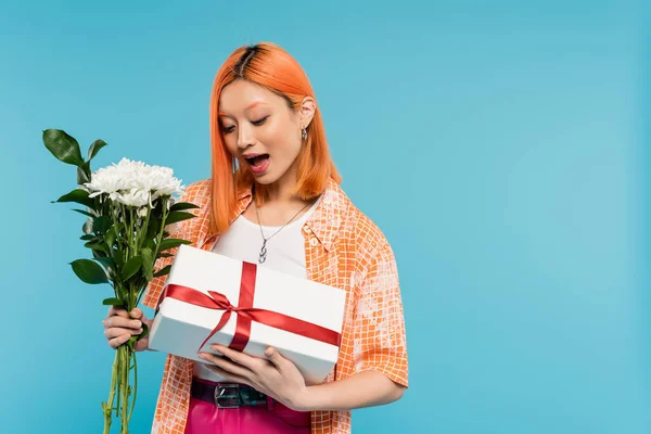 Floral bouquet, holiday, present, surprised and young asian woman with dyed hair holding white flowers and gift box on blue background, casual attire, generation z, festive celebration, birthday — Stock Photo