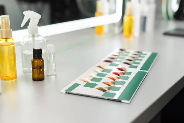Beauty industry, hair color palette and different hair salon tools on white surface, hair oil, spray bottles, salon work, hair extension, hair coloring, color selection, — Stock Photo