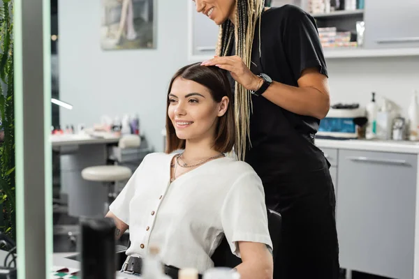 Beauty salon work, happy hairdresser with braids and female client, hairstyling, hair treatment, hairdo, extension, salon customer, beauty profession, client satisfaction, tattooed — Stock Photo