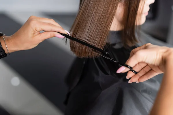 Haircut, cropped view of hairdresser cutting hair of female client, holding scissors and comb,  brunette short hair, professional, beauty worker, hairdo, salon job, salon customer — Stock Photo