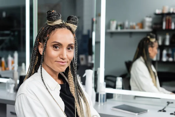 Happy woman in beauty salon, joyful client with braids looking at camera, customer satisfaction, hairstyle, female client with braids, mirror refection, hair buns, braided hair, portrait — Stock Photo