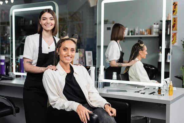 Client satisfaction, hairdresser and happy woman with braids, hairstyle, mirror, reflection, hair buns, braided hair, beauty salon, hair fashion, salon customer and hairstylist, looking at camera — Stock Photo