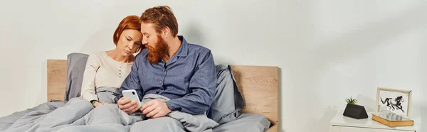 Digital couple, screen time, networking, relaxing on weekends without kids, sad husband and wife, bearded man and redhead woman using smartphone, day off, tattooed couple, interior, banner — Stock Photo